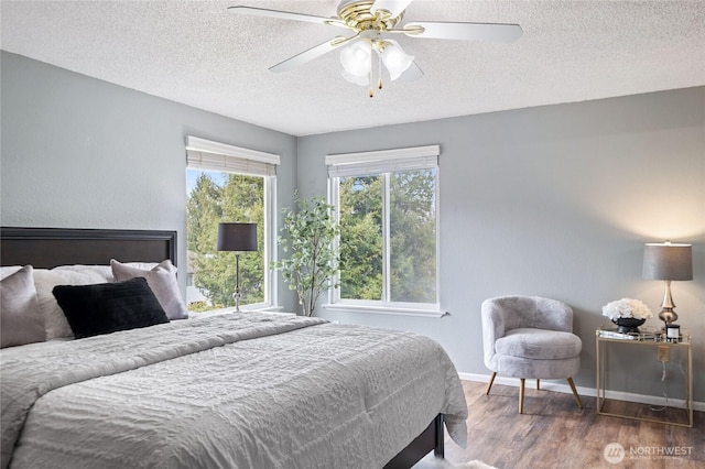 bedroom featuring a textured ceiling, a ceiling fan, baseboards, and wood finished floors