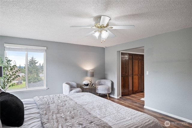 bedroom with a textured ceiling, wood finished floors, a closet, baseboards, and ceiling fan