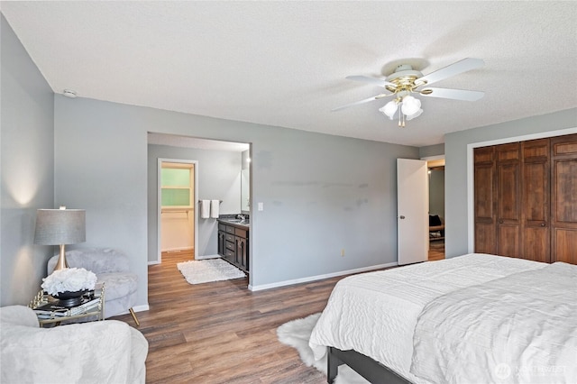 bedroom with dark wood-type flooring, ceiling fan, baseboards, a closet, and a textured ceiling