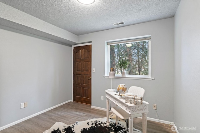 home office with visible vents, baseboards, a textured ceiling, and wood finished floors