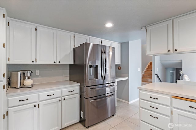 kitchen featuring white cabinetry, light countertops, light tile patterned floors, and stainless steel fridge