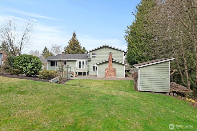 rear view of property featuring a chimney, an outdoor structure, and a yard