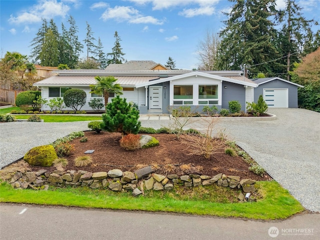 mid-century home with metal roof, gravel driveway, and an outdoor structure