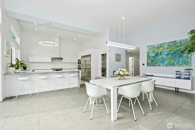 dining space featuring light tile patterned flooring, recessed lighting, and a high ceiling