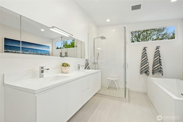 bathroom with visible vents, double vanity, a stall shower, a soaking tub, and a sink