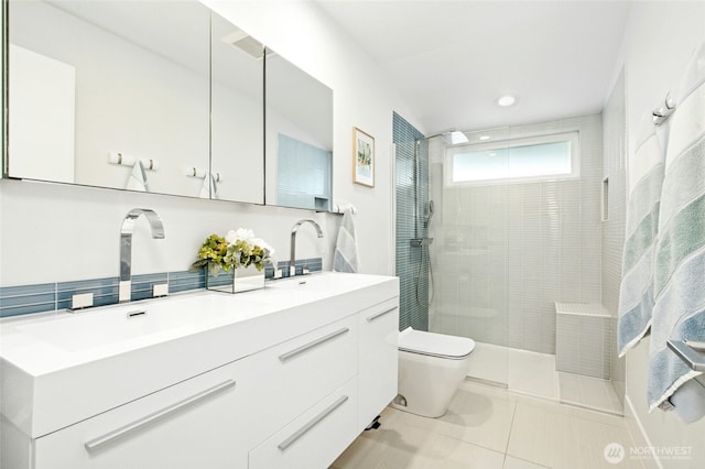 full bathroom featuring a sink, toilet, tile patterned flooring, and a tile shower