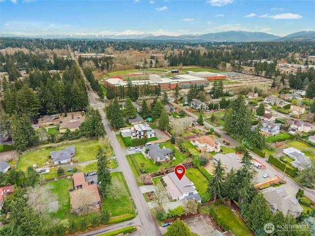 drone / aerial view featuring a residential view, a mountain view, and a wooded view