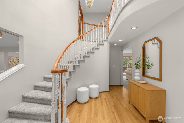 stairs featuring a high ceiling, wood finished floors, and baseboards