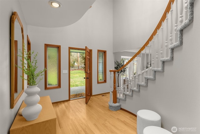 foyer with a towering ceiling, baseboards, wood finished floors, and stairs