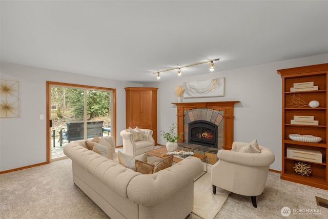 living room with light carpet, a tile fireplace, rail lighting, and baseboards