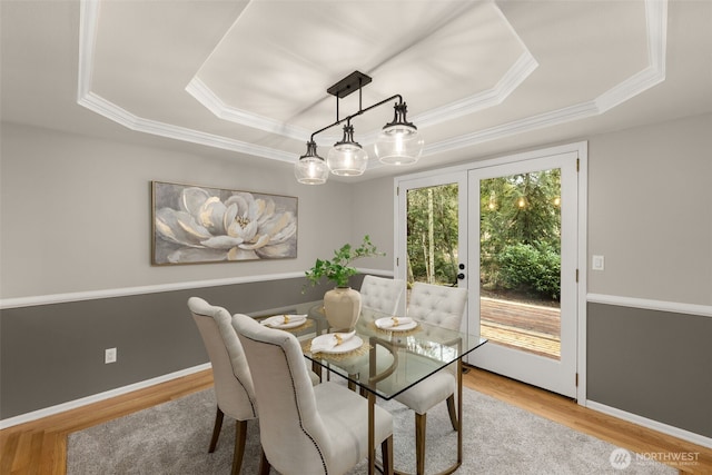 dining area featuring a tray ceiling, baseboards, and wood finished floors