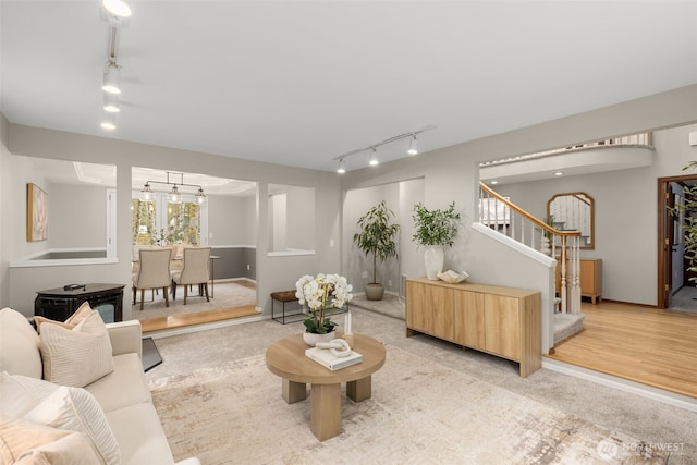 living room featuring stairs, rail lighting, and baseboards