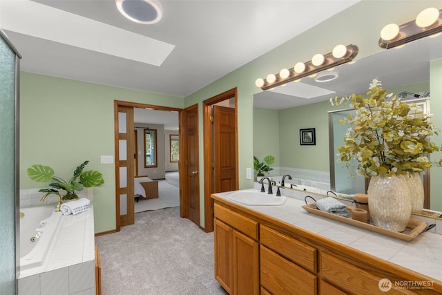 full bathroom featuring a skylight, vanity, and a whirlpool tub