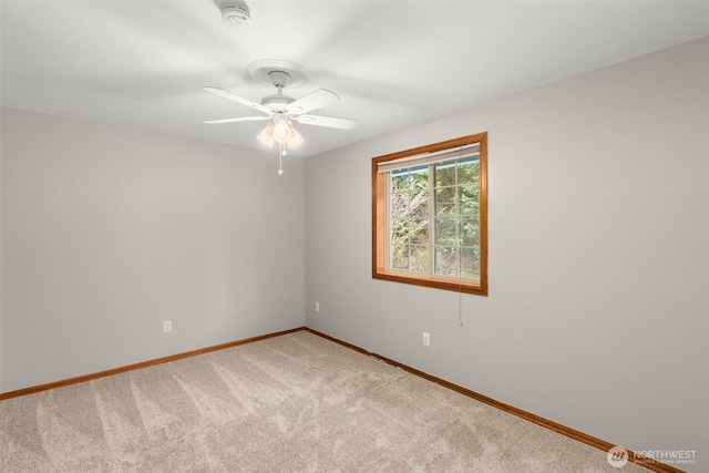 carpeted spare room featuring baseboards and ceiling fan