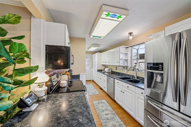 kitchen with dark countertops, light wood-type flooring, white cabinets, stainless steel appliances, and open shelves