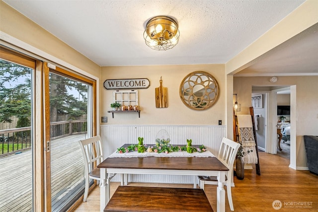 dining room with a wainscoted wall, a textured ceiling, and wood finished floors