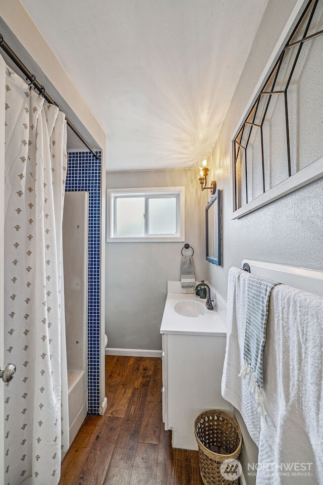 bathroom featuring vanity, shower / bathtub combination with curtain, baseboards, wood-type flooring, and toilet