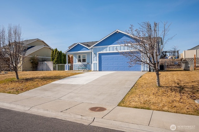 ranch-style house with a front yard, fence, driveway, an attached garage, and board and batten siding