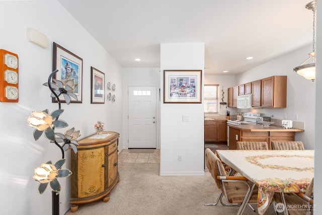 kitchen featuring recessed lighting, white appliances, light carpet, and brown cabinets