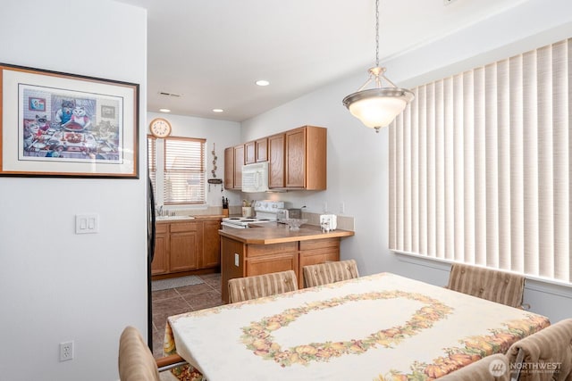 kitchen featuring white appliances, visible vents, recessed lighting, hanging light fixtures, and light countertops