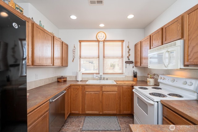 kitchen with visible vents, recessed lighting, brown cabinetry, white appliances, and a sink