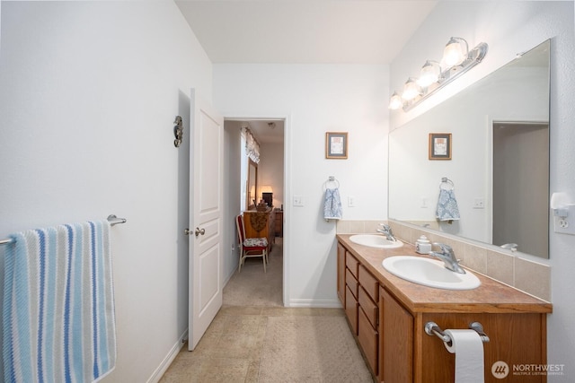 full bath with double vanity, ensuite bath, baseboards, and a sink