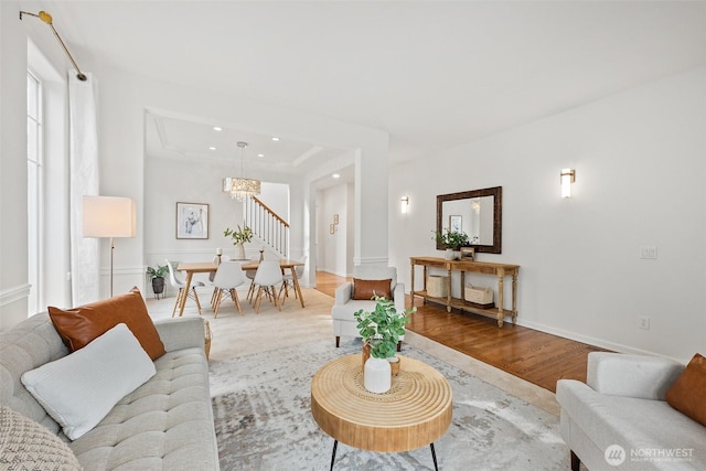 living room with baseboards, stairway, recessed lighting, an inviting chandelier, and wood finished floors