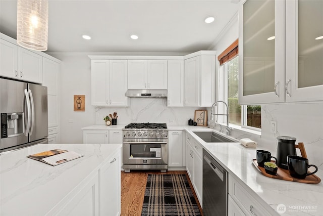 kitchen featuring a sink, decorative backsplash, stainless steel appliances, white cabinets, and exhaust hood