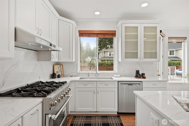 kitchen featuring a sink, stainless steel appliances, white cabinets, glass insert cabinets, and under cabinet range hood