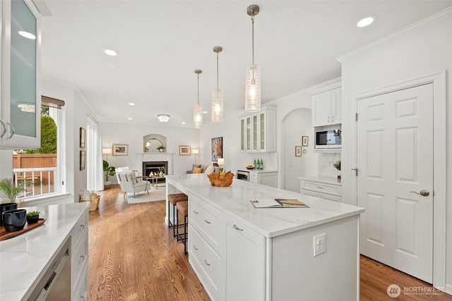 kitchen featuring glass insert cabinets, open floor plan, white cabinetry, crown molding, and built in microwave