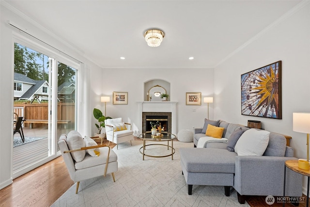 living area featuring light wood-style flooring, recessed lighting, a warm lit fireplace, and ornamental molding