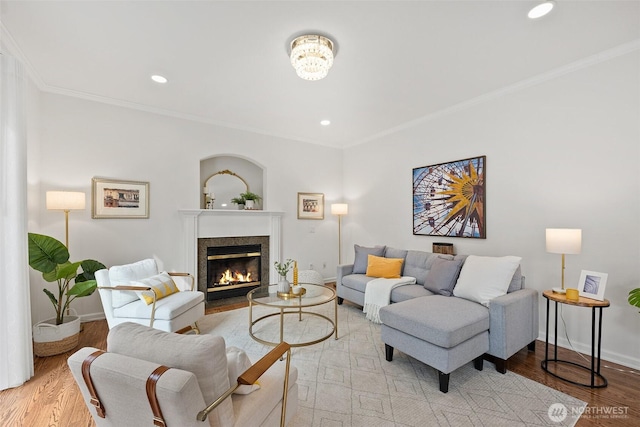 living room with a high end fireplace, light wood-type flooring, baseboards, and ornamental molding