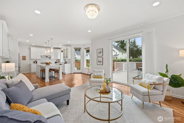 living room featuring baseboards, light wood-style flooring, recessed lighting, crown molding, and a chandelier