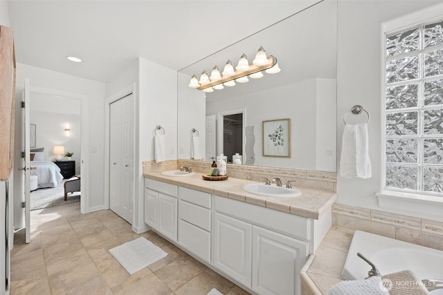 full bathroom with a sink, a closet, a bath, and double vanity