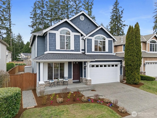 view of front of house with fence, an attached garage, covered porch, stone siding, and aphalt driveway