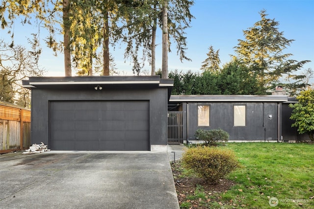 mid-century home with a garage, concrete driveway, a front lawn, and fence