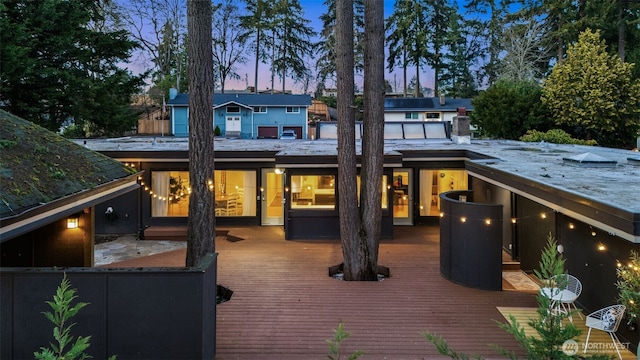 back of property at dusk with a wooden deck