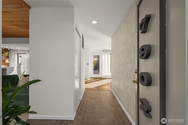 hallway with brick floor, baseboards, recessed lighting, and wallpapered walls