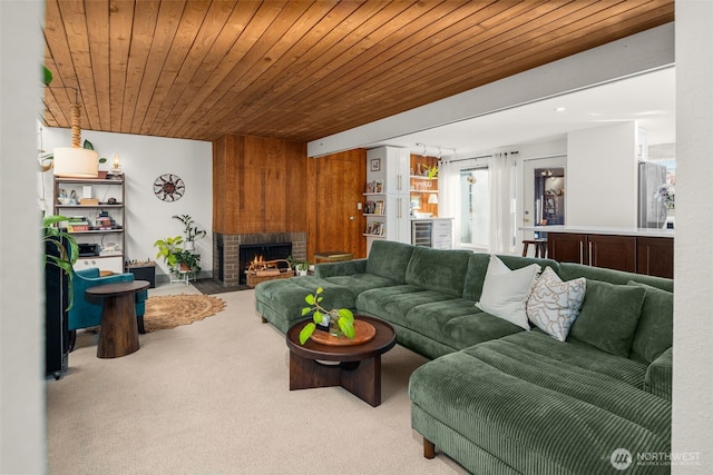 carpeted living room with a fireplace and wood ceiling