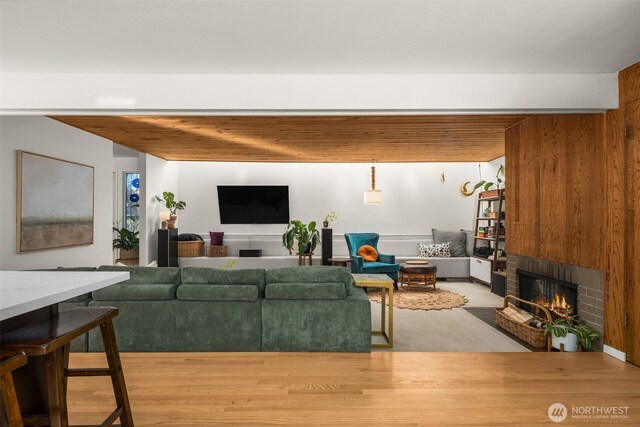 living area with wood finished floors, beamed ceiling, a fireplace, and wood walls