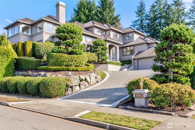 view of front of property featuring concrete driveway and a chimney