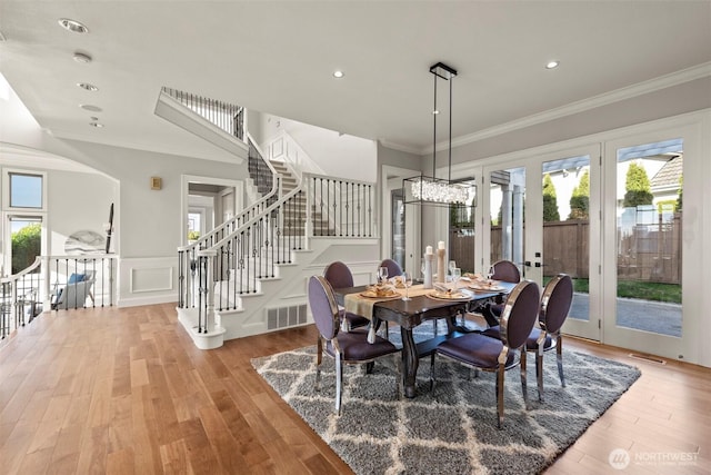 dining space with a wealth of natural light, visible vents, wood finished floors, and crown molding