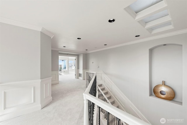 hallway with light carpet, an upstairs landing, a wainscoted wall, and ornamental molding