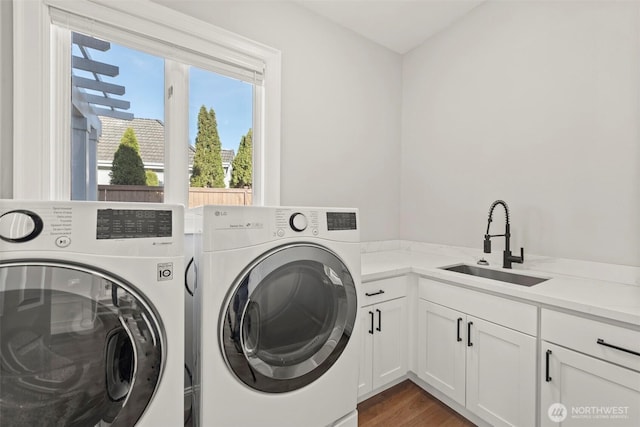 washroom with cabinet space, washer and dryer, wood finished floors, and a sink