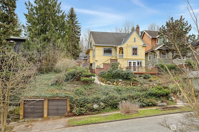 view of front facade featuring a chimney, concrete driveway, a garage, a deck, and brick siding