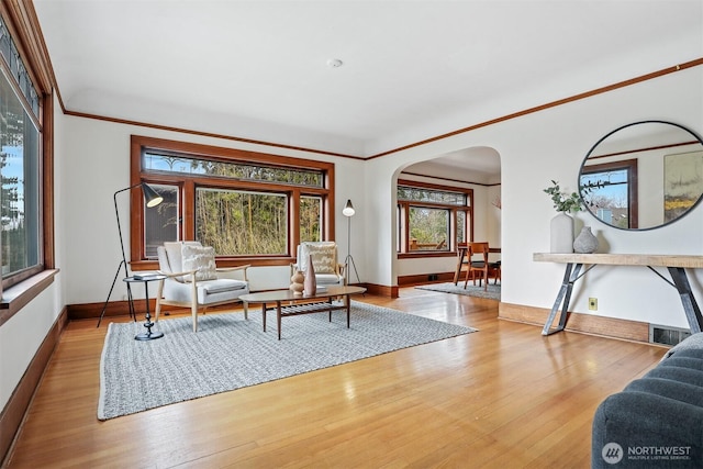 interior space with baseboards, arched walkways, hardwood / wood-style floors, and crown molding