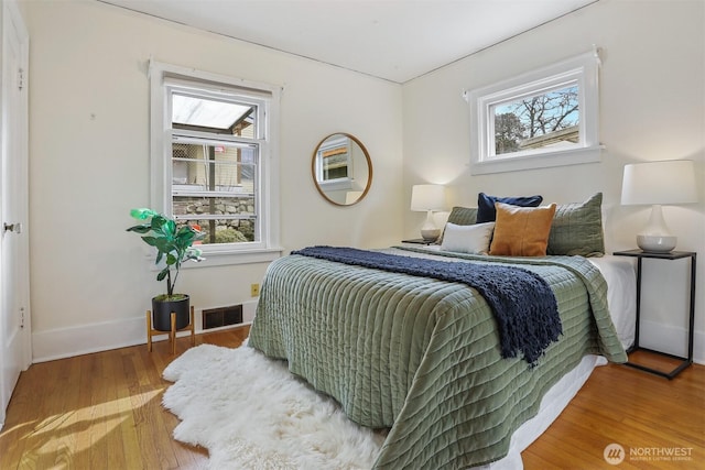 bedroom with visible vents, wood finished floors, and baseboards