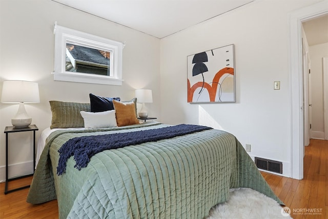 bedroom with visible vents, baseboards, and wood finished floors