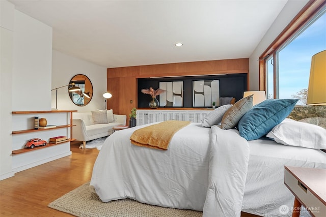 bedroom with an accent wall, wooden walls, recessed lighting, and wood finished floors