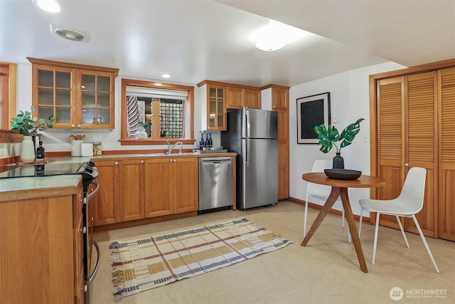 kitchen with visible vents, glass insert cabinets, brown cabinets, stainless steel appliances, and a sink